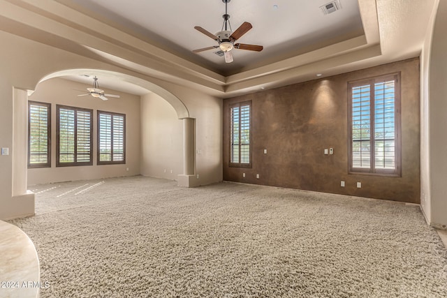 carpeted spare room with ceiling fan and a raised ceiling