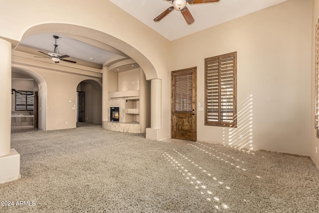 unfurnished living room featuring a premium fireplace, carpet floors, and ceiling fan