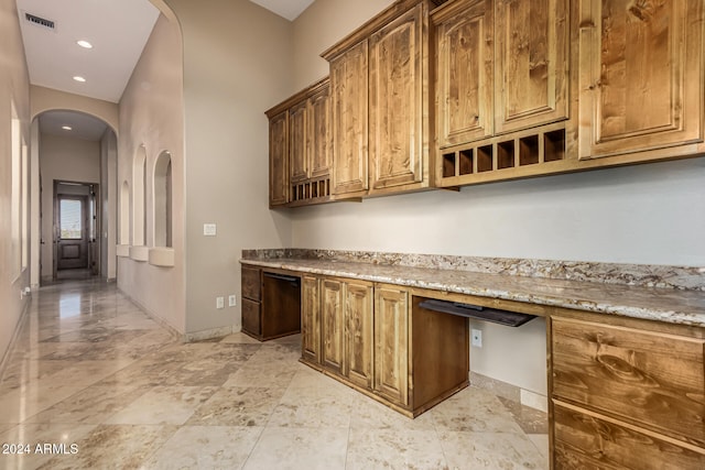 interior space with light stone countertops and built in desk