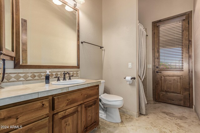 bathroom with vanity, decorative backsplash, and toilet