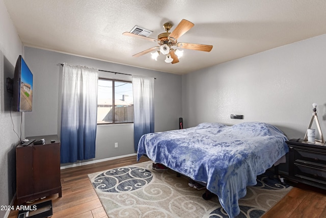 bedroom with hardwood / wood-style floors, a textured ceiling, and ceiling fan