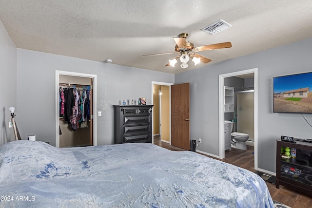 bedroom featuring ensuite bath, ceiling fan, a spacious closet, a textured ceiling, and dark hardwood / wood-style flooring