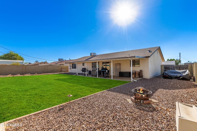 back of house with a yard, a patio, and a fire pit