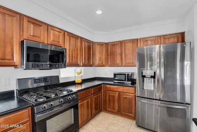 941 E Stirrup Ln, San Tan Valley, AZ 85143 - kitchen featuring stainless steel appliances, dark countertops, light tile patterned floors, brown cabinets, and recessed lighting
