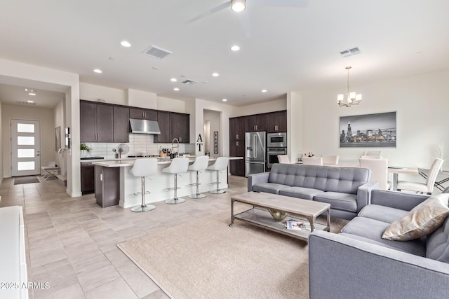 living room with visible vents, recessed lighting, and ceiling fan with notable chandelier