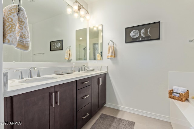 bathroom with double vanity, a sink, tile patterned floors, and baseboards