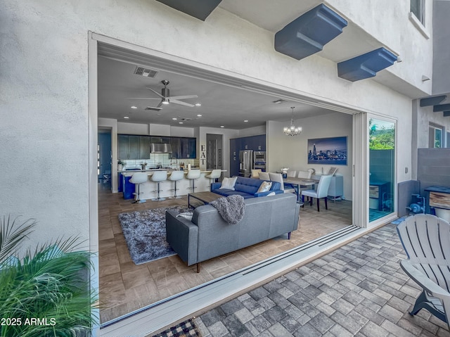 living area with visible vents and ceiling fan with notable chandelier