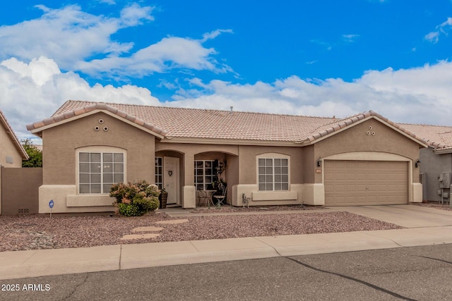 mediterranean / spanish-style home with stucco siding, a tiled roof, concrete driveway, and an attached garage