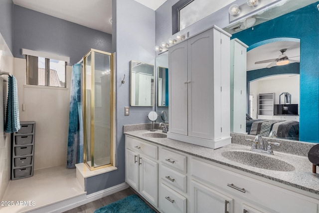 ensuite bathroom featuring connected bathroom, a stall shower, a ceiling fan, and a sink