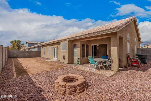 rear view of property featuring stucco siding, a patio, a fire pit, and a fenced backyard