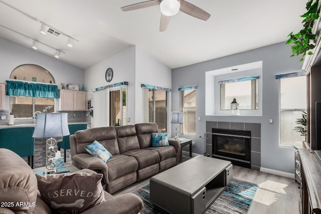 living area featuring a wealth of natural light, lofted ceiling, and a tiled fireplace