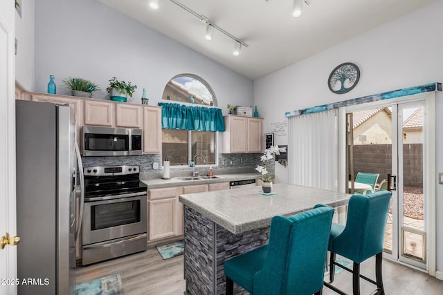 kitchen featuring light brown cabinets, a sink, decorative backsplash, light countertops, and appliances with stainless steel finishes