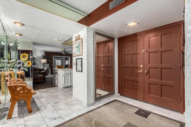 foyer featuring ceiling fan and a textured ceiling