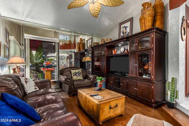 living room featuring dark hardwood / wood-style floors, ceiling fan, lofted ceiling, and a textured ceiling