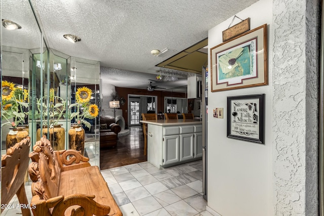 kitchen with kitchen peninsula, ceiling fan, light tile patterned floors, and a textured ceiling