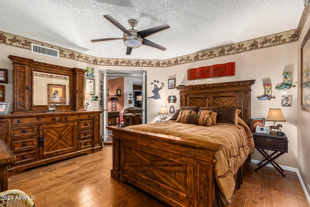 bedroom with a textured ceiling, hardwood / wood-style flooring, and ceiling fan