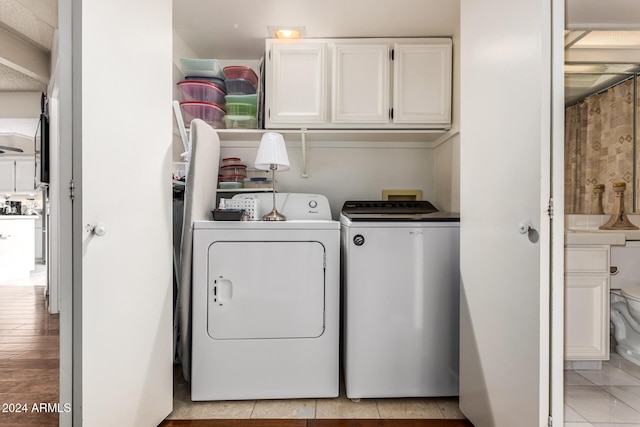 laundry area with cabinets, independent washer and dryer, and light hardwood / wood-style flooring