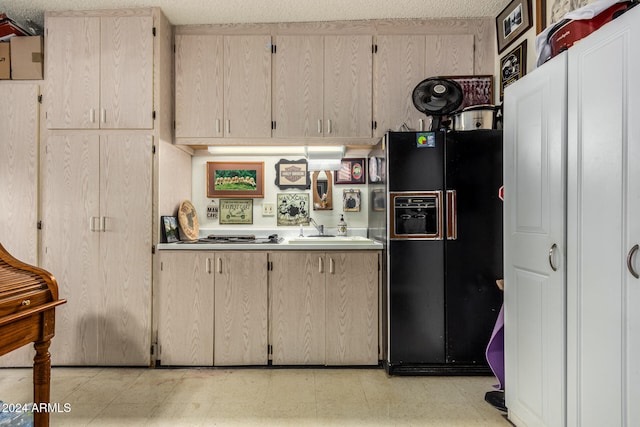 kitchen featuring black fridge with ice dispenser and a textured ceiling