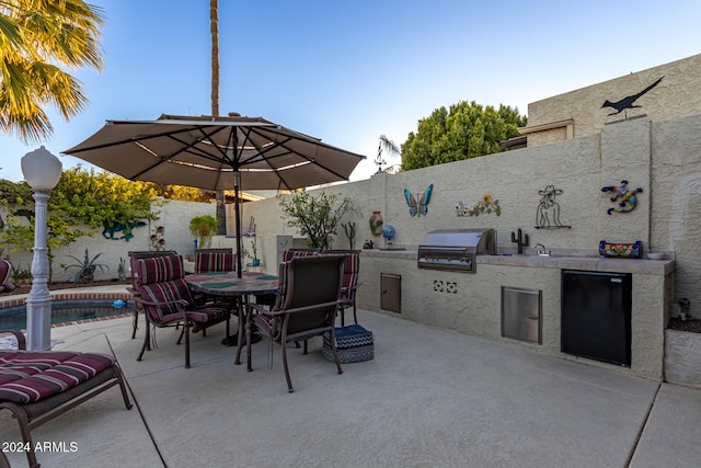 view of patio / terrace featuring a grill, a fenced in pool, and exterior kitchen