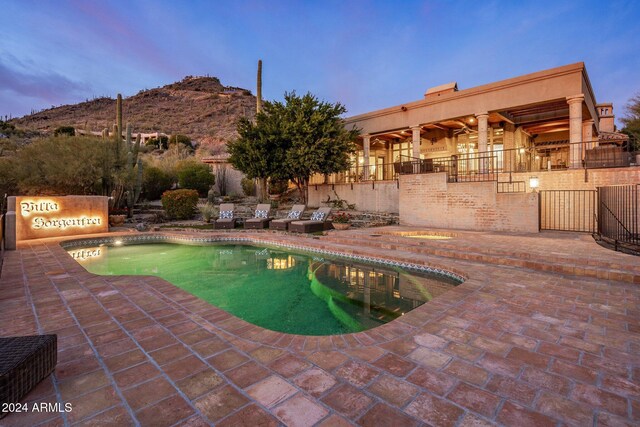 pool at dusk with a mountain view, a patio area, and central air condition unit