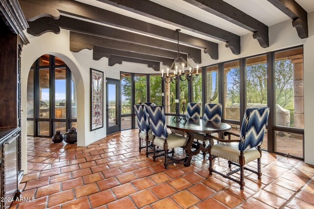 dining room with a healthy amount of sunlight, a notable chandelier, and beamed ceiling