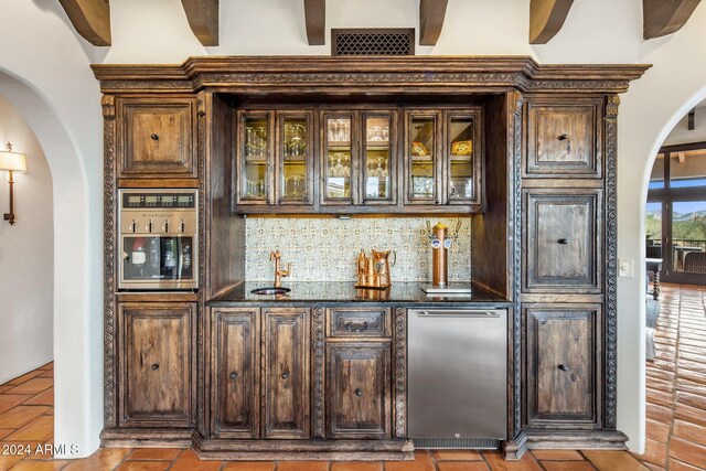 bar with dark brown cabinetry, decorative backsplash, and beamed ceiling