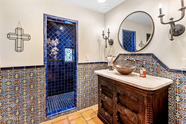 bathroom with tiled shower, vanity, tile patterned flooring, and tile walls