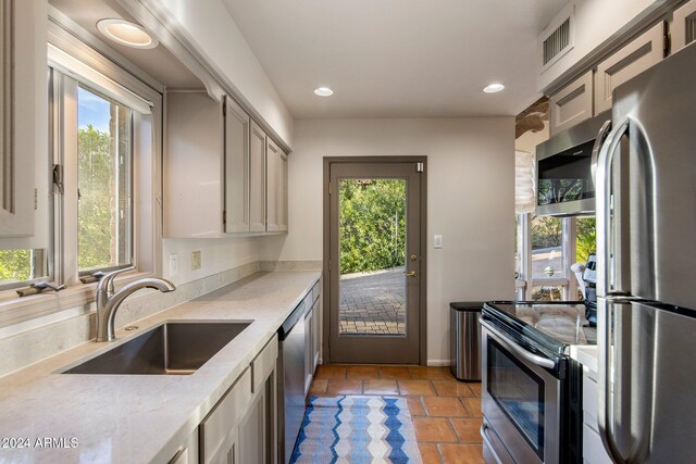 kitchen with appliances with stainless steel finishes, sink, light tile patterned floors, and plenty of natural light