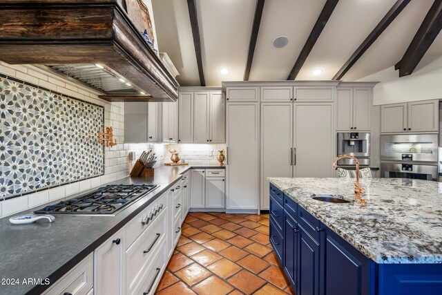 kitchen featuring blue cabinetry, sink, white cabinetry, tasteful backsplash, and beamed ceiling