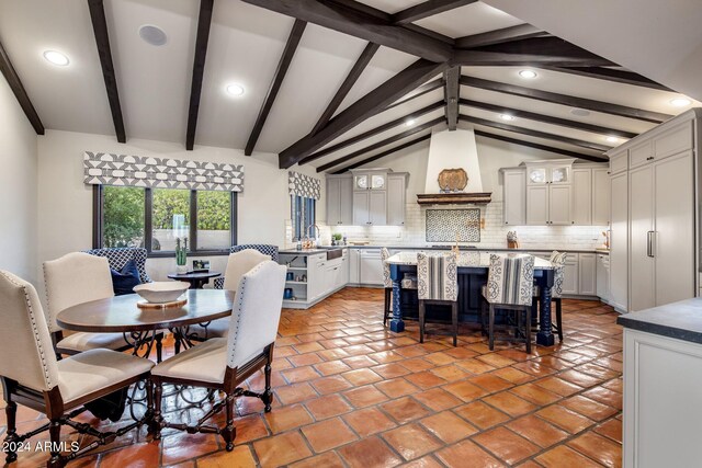 tiled dining area featuring sink and lofted ceiling with beams