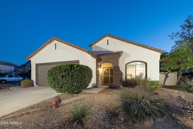 mediterranean / spanish-style house with stucco siding, concrete driveway, an attached garage, fence, and a tiled roof