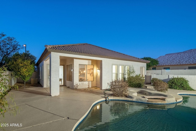 rear view of house with a fenced in pool, a patio, a fenced backyard, a tiled roof, and stucco siding