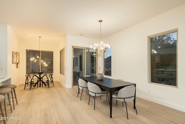 dining space featuring light wood-style floors, baseboards, and an inviting chandelier