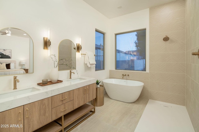 full bath with a tile shower, double vanity, a soaking tub, and a sink