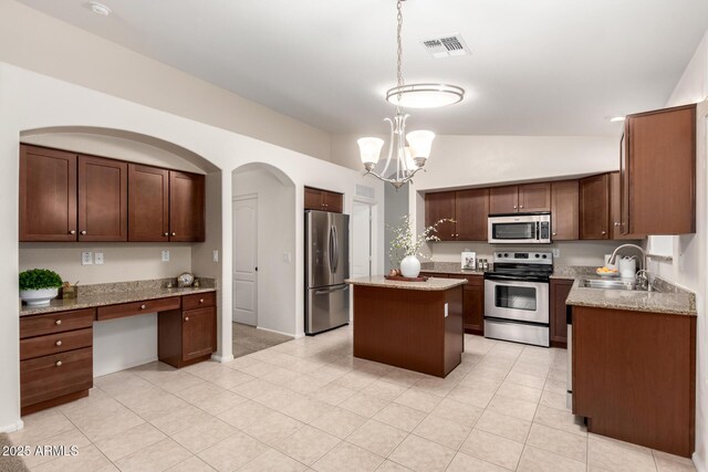 kitchen with visible vents, built in study area, a sink, vaulted ceiling, and appliances with stainless steel finishes