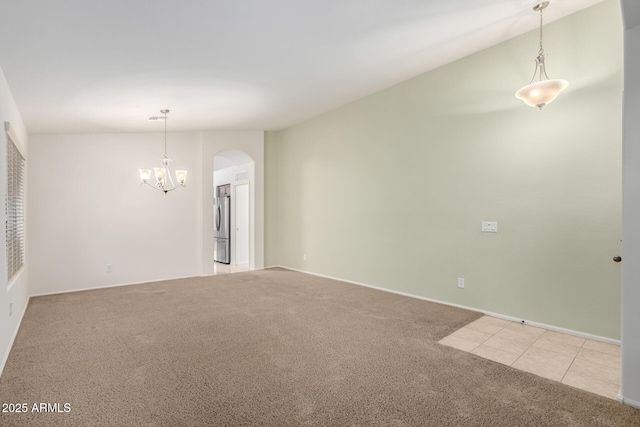 carpeted spare room featuring arched walkways and a notable chandelier