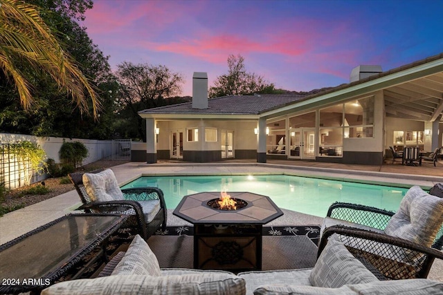 pool at dusk with a fire pit and a patio