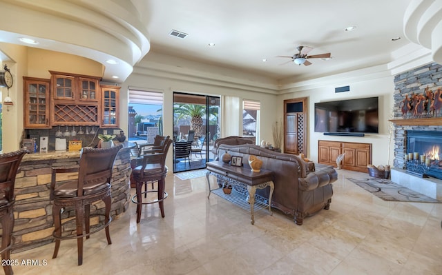 living room with ceiling fan, indoor bar, and a fireplace