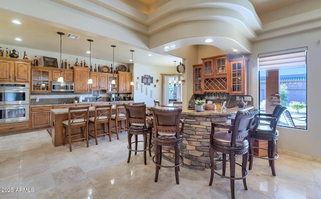 kitchen with decorative light fixtures, a breakfast bar, backsplash, and stainless steel appliances