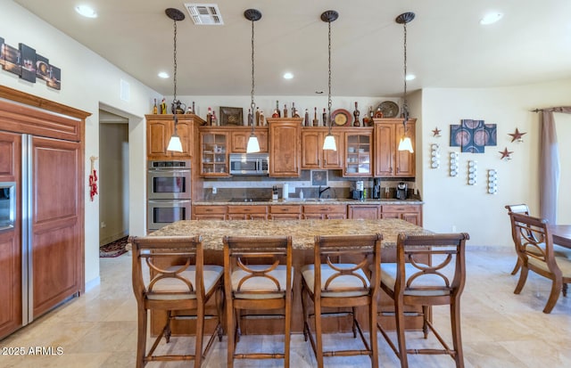 kitchen featuring backsplash, a kitchen island, hanging light fixtures, appliances with stainless steel finishes, and a breakfast bar area