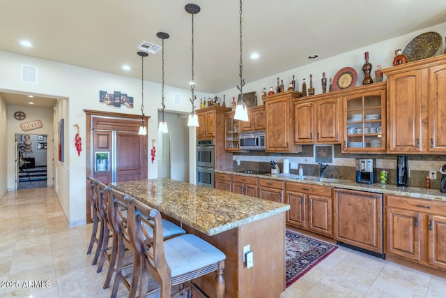 kitchen with appliances with stainless steel finishes, pendant lighting, decorative backsplash, and a kitchen island