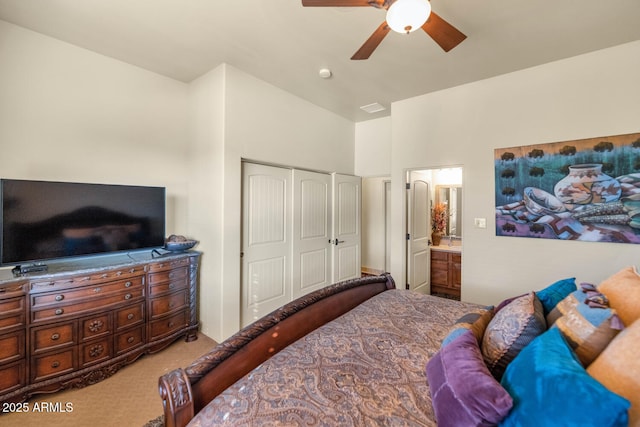 carpeted bedroom with a closet, ceiling fan, and ensuite bath