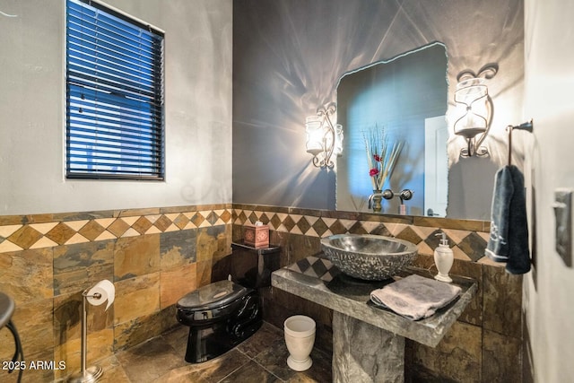 bathroom featuring toilet, tile walls, and sink