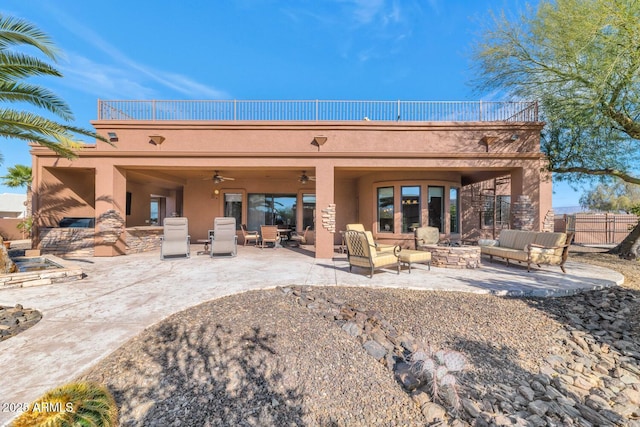 back of house with ceiling fan, an outdoor living space with a fireplace, and a patio