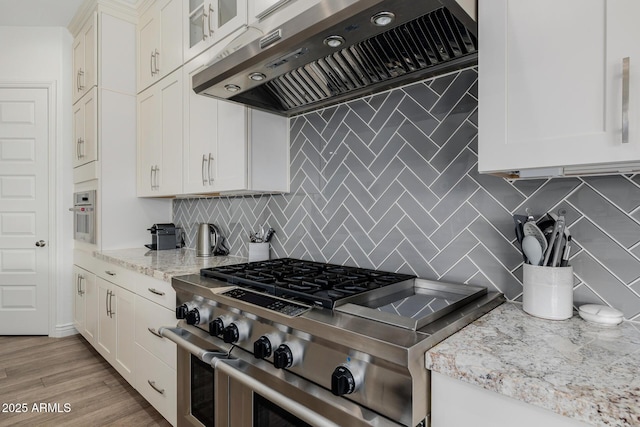 kitchen with white cabinetry, high end stainless steel range, light hardwood / wood-style floors, and wall chimney exhaust hood