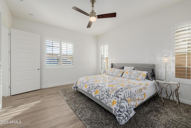 bedroom featuring multiple windows, ceiling fan, and light hardwood / wood-style flooring