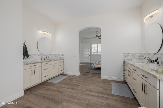 bathroom featuring ceiling fan, wood-type flooring, vanity, and backsplash