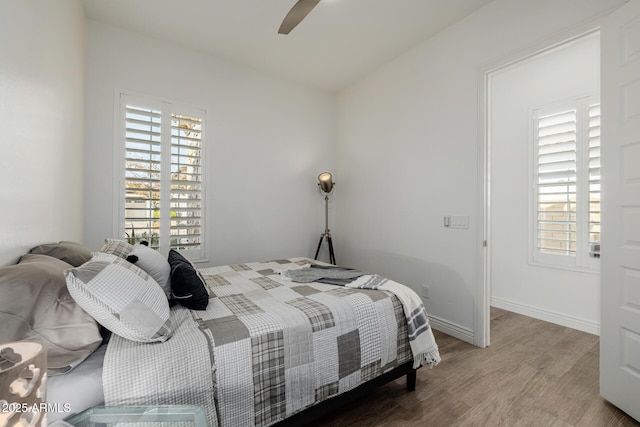 bedroom with multiple windows, hardwood / wood-style floors, and ceiling fan