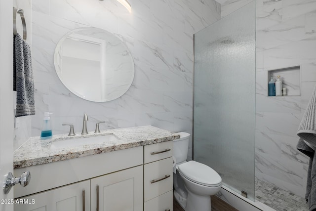 bathroom featuring vanity, a shower with shower door, tile walls, and toilet