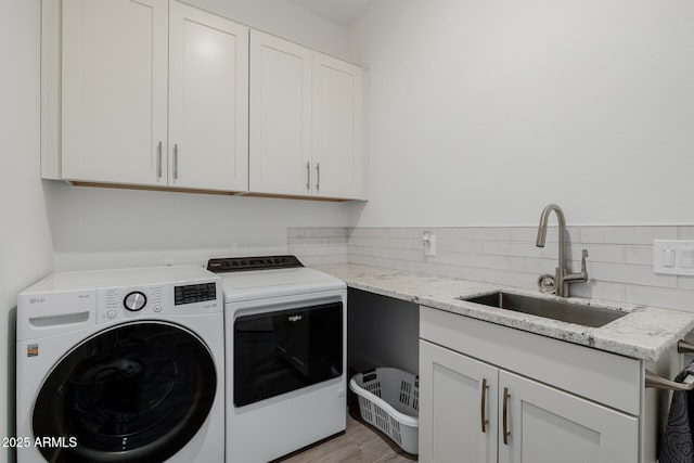 laundry area featuring cabinets, sink, washer and dryer, and light wood-type flooring